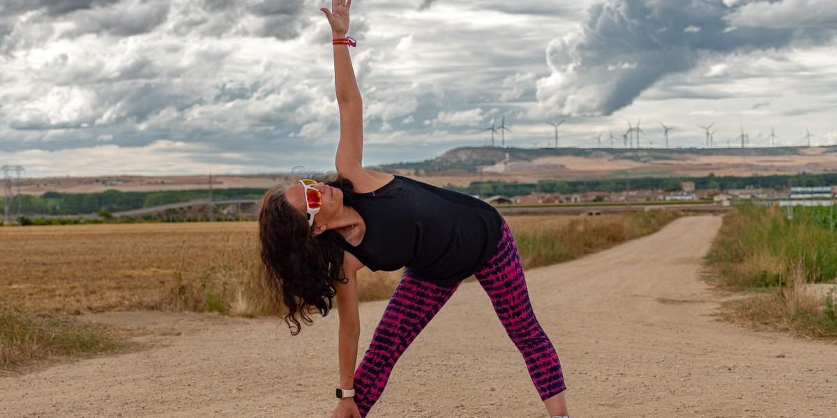 Outdoor fitness scene of a woman stretching on a dirt path in Soto de Cerrato amidst scenic landscapes.