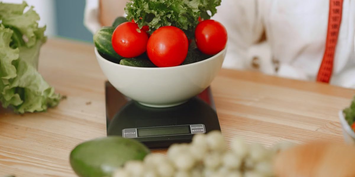 Colorful fresh vegetables including tomatoes and cucumbers on a kitchen scale for healthy eating.