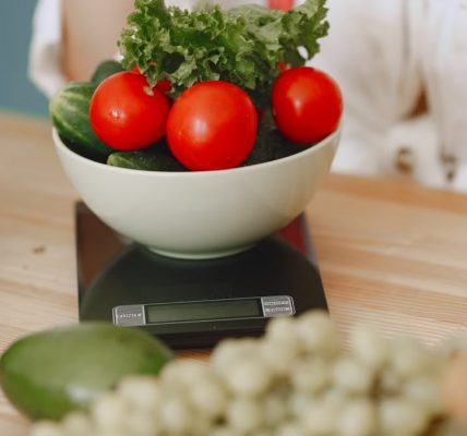 Colorful fresh vegetables including tomatoes and cucumbers on a kitchen scale for healthy eating.
