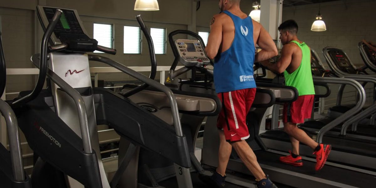 Two men running on treadmills in a modern gym, promoting fitness and health.