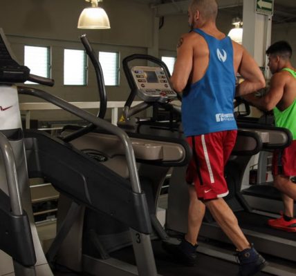 Two men running on treadmills in a modern gym, promoting fitness and health.